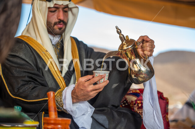 الاحتفال بعيد ومناسبة وطنية, يوم بدينا 1727 م، الشموخ والاعتزاز والفخر, ارتداء الزي الشعبي في يوم تأسيس الدولة السعودية الأولى 22 فبراير, رجل عربي خليجي سعودي يرتدي البشت والغترة والعقال الذهبي العريض يقوم بصب فنجان من القهوة, اتباع التقاليد في كرم الضيافة