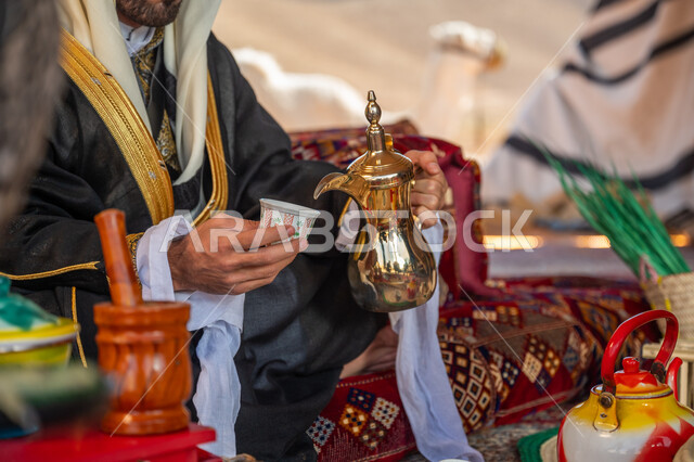 التقاليد والعادات العربية و كرم الضيافة، الاحتفال بعيد ومناسبة وطنية, يوم بدينا 1727م، الشموخ والاعتزاز والفخر, ارتداء الزي الشعبي في يوم تأسيس الدولة السعودية الأولى 22 فبراير, صورة مقربة ليدي رجل عربي خليجي سعودي يرتدي البشت والغترة يقوم بصب فنجان من القهوة