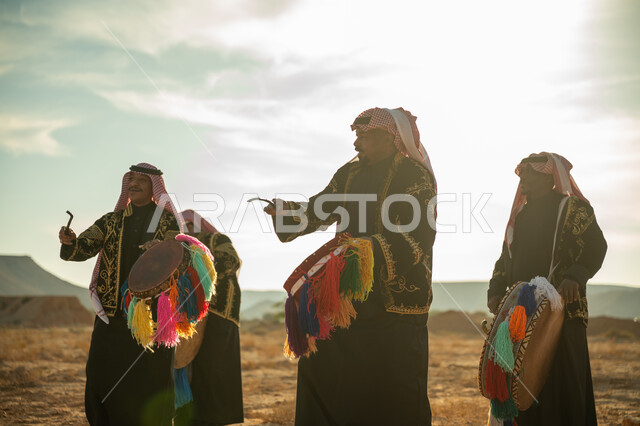 الأهازيج والرقص التقليدي، فرقة رجال لعروض الفلكلور التراثي في احدى المناطق الصحراوية بالمملكة، ارتداء الزي الشعبي المطرز والشماغ في مناسبة وطنية، يوم بدينا ٢٢ فبراير، ذكرى تأسيس الدوله السعوديه الأولى ١٧٢٧ م، الاحتفال بالعيد الوطني بقرع الطبل المزين بخيوط ملونة