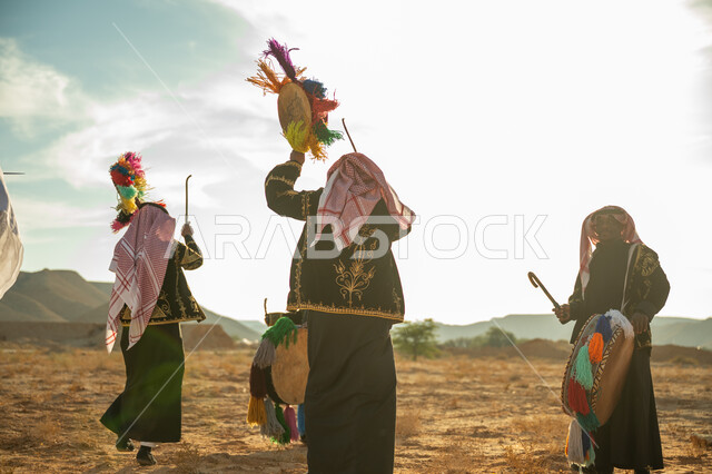 فرقة رجال لعروض الفلكلور التراثي في احدى المناطق الصحراوية بالمملكة، ارتداء الزي الشعبي المطرز والشماغ في مناسبة وطنية، يوم بدينا ٢٢ فبراير، ذكرى تأسيس الدوله السعوديه الأولى ١٧٢٧ م، الاحتفال بالعيد الوطني بقرع الطبل المزين بخيوط ملونة، الأهازيج والرقص التقليدي