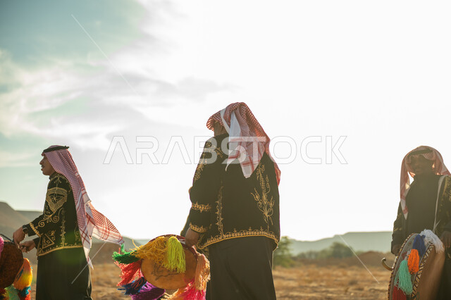 فرقة رجال لعروض الفلكلور التراثي في احدى المناطق الصحراوية بالمملكة، ارتداء الزي الشعبي المطرز والشماغ في مناسبة وطنية، يوم بدينا ٢٢ فبراير، ذكرى تأسيس الدوله السعوديه الأولى ١٧٢٧ م، الاحتفال بالعيد الوطني بقرع الطبل المزين بخيوط ملونة، الأهازيج والرقص التقليدي