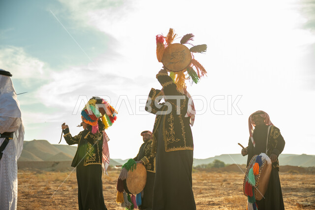 الأهازيج والرقص التقليدي، فرقة رجال لعروض الفلكلور التراثي في احدى المناطق الصحراوية بالمملكة، ارتداء الزي الشعبي المطرز والشماغ في مناسبة وطنية، يوم بدينا ٢٢ فبراير، ذكرى تأسيس الدوله السعوديه الأولى ١٧٢٧ م، الاحتفال بالعيد الوطني بقرع الطبل المزين بخيوط ملونة