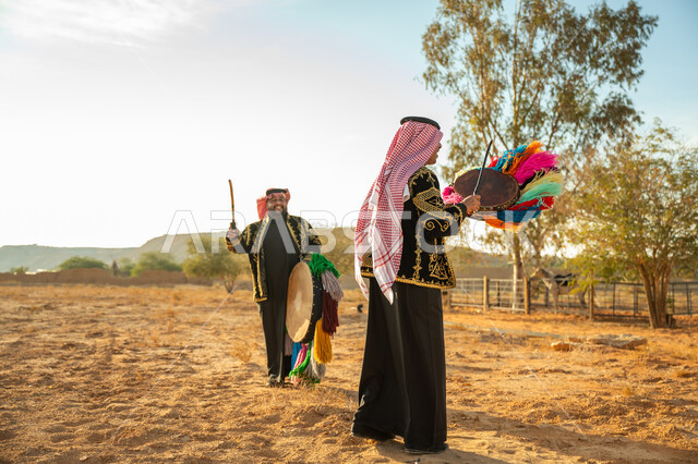 الأهازيج والرقص التقليدي، فرقة رجال لعروض الفلكلور التراثي في احدى المناطق الصحراوية بالمملكة، ارتداء الزي الشعبي المطرز والشماغ في مناسبة وطنية، يوم بدينا ٢٢ فبراير، ذكرى تأسيس الدوله السعوديه الأولى ١٧٢٧ م، الاحتفال بالعيد الوطني بقرع الطبل المزين بخيوط ملونة