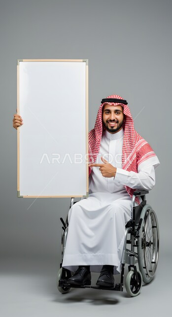موك اب مربع أبيض، إعلان وعرض تسويقي، استخدام وسيلة تعليمية وتوضيحية، بورتريه لشاب عربي خليجي سعودي مقعد مبتسم يرتدي الثوب التقليدي والشماغ يجلس على كرسي متحرك يحمل بيده لوحة بيضاء فارغة يشير إليها بإصبع السبابة، خلفية رمادية