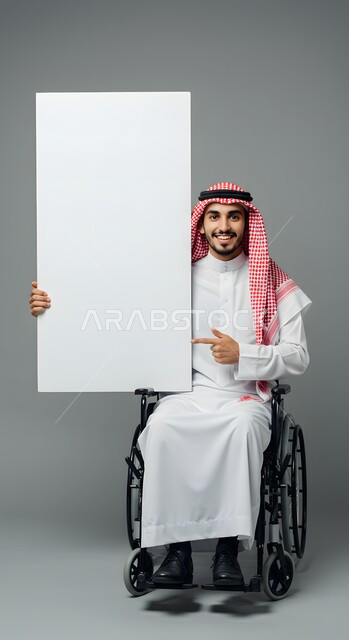 موك اب مربع أبيض، إعلان وعرض تسويقي، استخدام وسيلة تعليمية وتوضيحية، بورتريه لشاب عربي خليجي سعودي مقعد مبتسم يرتدي الثوب التقليدي والشماغ يجلس على كرسي متحرك يحمل بيده لوحة بيضاء فارغة يشير إليها بإصبع السبابة، خلفية رمادية