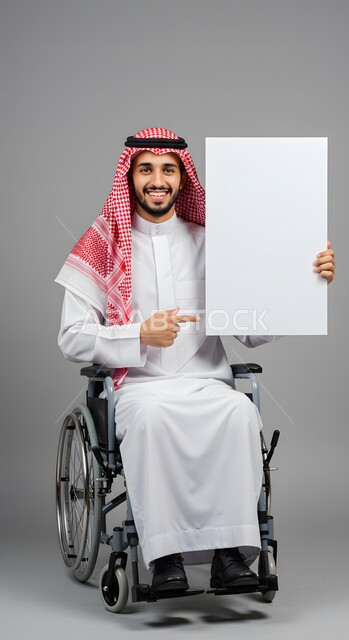 إعلان وعرض تسويقي، موك اب مربع أبيض، استخدام وسيلة تعليمية وتوضيحية، بورتريه لشاب عربي خليجي سعودي مقعد مبتسم يرتدي الثوب التقليدي والشماغ يجلس على كرسي متحرك يحمل بيده لوحة بيضاء فارغة يشير إليها بإصبع السبابة، خلفية رمادية
