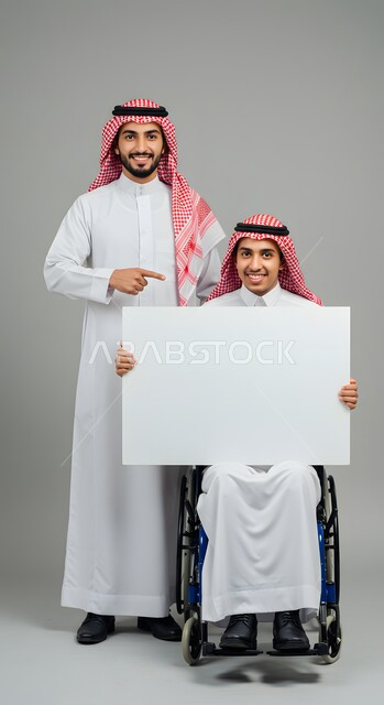 موك اب مربع أبيض، استخدام وسيلة تعليمية وتوضيحية، إعلان وعرض تسويقي، بورتريه لشاب عربي خليجي سعودي مبتسم مقعد يرتدي الثوب التقليدي والشماغ يجلس على كرسي متحرك يحمل بيده لوحة بيضاء فارغة يقف بجانب صديقه يشير إليها بإصبع السبابة، خلفية رمادية