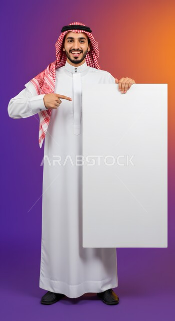 موك اب مربع أبيض، إعلان وعرض تسويقي، استخدام لوحة توضيحية ووسيلة تعليمية، بورتريه لشاب عربي خليجي سعودي مبتسم يرتدي الثوب التقليدي والشماغ يشير بإصبع السبابة إلى لوحه بيضاء مربعه فارغة ينظر إلى الكاميرا بإيماءات السرور، صورة الجسم بالطول الكامل، خلفية ملونة