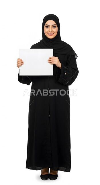 استخدام وسيلة توضيحية تعليمية، إعلان وعرض تسويقي، موك اب مربع أبيض، بورتريه لسيدة عربية خليجية سعودية مبتسمة محجبة ترتدي العباءة السوداء تمسك بيدها لوحه بيضاء مربعه فارغة تنظر إلى الكاميرا بإيماءات السرور، صورة الجسم بالطول الكامل، خلفية بيضاء