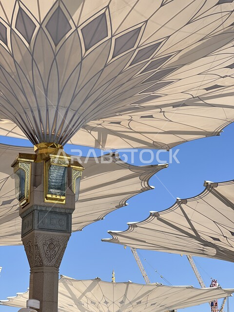 The concept of worship and getting closer to God, a famous Islamic religious holy place in Saudi Arabia, a close-up of electronic umbrellas in the courtyard of the Haram in Medina, the architectural art of the Prophet's Mosque, performing the obligatory prayer on time
