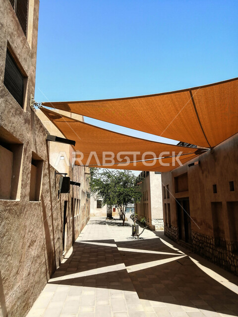 صورة لأشرعة على السقف بين المباني , مظلات قماشية تحمي من أشعة الشمس , تصاميم تشبه الشراع تعطي ظل للمكان .