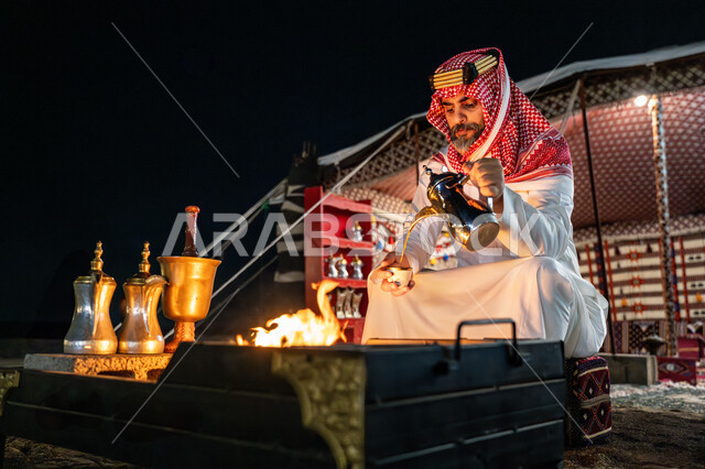 احتفال و مناسبة وطنية, اجواء شتوية ليلية, يوم بدينا 22 فبراير، ذكرى تاسيس الدوله السعوديه الاولى 1727م, رجل عربي خليجي سعودي يرتدي الشماغ و الثوب التقليدي يقوم بصب القهوة, خيمة شعبية في الصحراء، مفهوم حسن الضيافة والاستقبال عند العرب