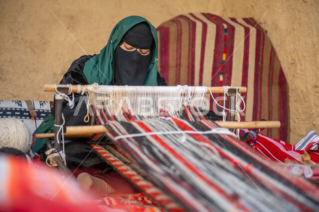 صناعة تقليدية تاريخية، حرفة ومهنة يدوية قديمة، يوم بدينا ٢٢ فبراير، سيدة عربية خليجية سعودية ترتدي العباءة والبرقع تقوم بنسج وغزل الصوف، ذكرى تاسيس الدوله السعوديه الاولى ١٧٢٧م، منتج وطني محلي, إحياء التراث الشعبي السعودي