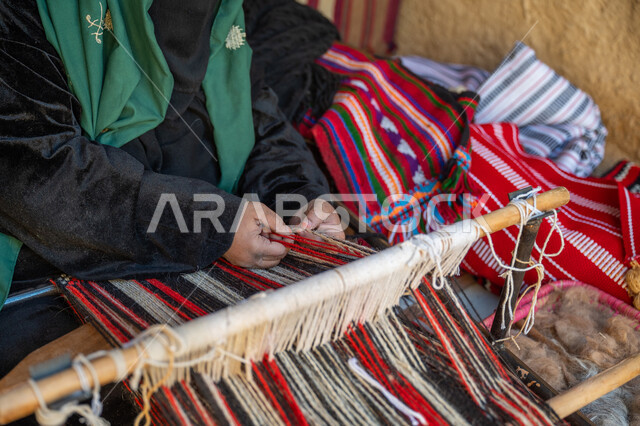 حرفة ومهنة يدوية قديمة، صناعة تقليدية تاريخية، منتج وطني محلي, يوم بدينا ٢٢ فبراير، صورة مقربة لأيدي سيدة عربية خليجية سعودية ترتدي العباءة والبرقع تقوم بنسج وغزل الصوف, ذكرى تاسيس الدوله السعوديه الاولى ١٧٢٧م، احياء التراث الشعبي السعودي