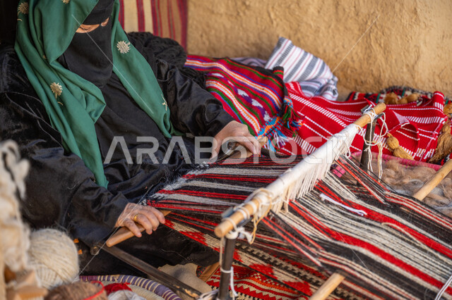 ذكرى تاسيس الدوله السعوديه الاولى ١٧٢٧م, مهنة وحرفة يدوية قديمة، منتج وطني محلي, يوم بدينا ٢٢ فبراير، صناعة تقليدية تاريخية، صورة من الجانب لسيدة عربية خليجية سعودية ترتدي العباءة والبرقع تقوم بنسج وغزل الصوف، احياء التراث الشعبي السعودي