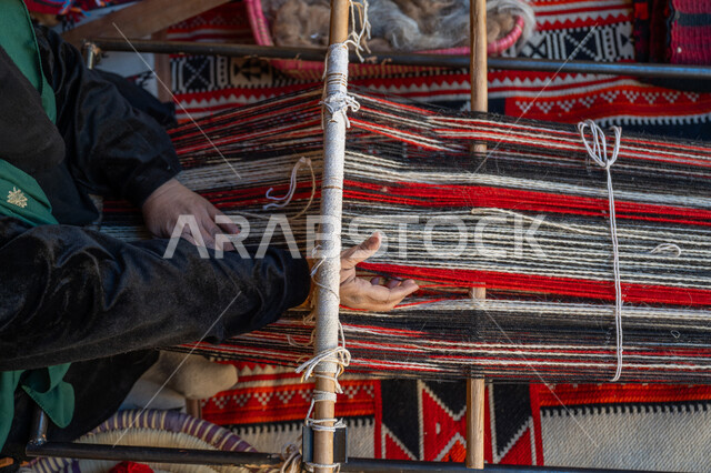 صناعة تقليدية تاريخية, حرفة ومهنة يدوية قديمة، ذكرى تاسيس الدوله السعوديه الاولى ١٧٢٧م، منتج وطني محلي, يوم بدينا ٢٢ فبراير، صورة من الاعلى لأيدي سيدة عربية خليجية سعودية ترتدي العباءة والبرقع تقوم بنسج وغزل الصوف، احياء التراث الشعبي السعودي