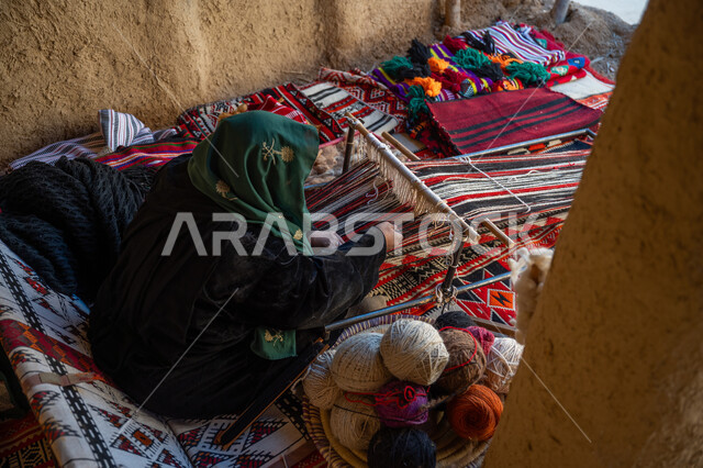 يوم بدينا ٢٢ فبراير، ذكرى تاسيس الدوله السعوديه الاولى ١٧٢٧م، منتج وطني محلي, صناعة تقليدية تاريخية، صورة من الاعلى لسيدة عربية خليجية سعودية ترتدي العباءة تقوم بنسج وغزل الصوف, مهنة وحرفة يدوية قديمة، احياء التراث الشعبي السعودي