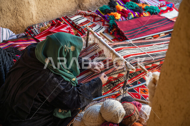 ذكرى تاسيس الدوله السعوديه الاولى ١٧٢٧م، يوم بدينا ٢٢ فبراير، منتج وطني محلي, صناعة تقليدية تاريخية، صورة من الاعلى لسيدة عربية خليجية سعودية ترتدي العباءة تقوم بنسج وغزل الصوف, مهنة وحرفة يدوية قديمة، احياء التراث الشعبي السعودي