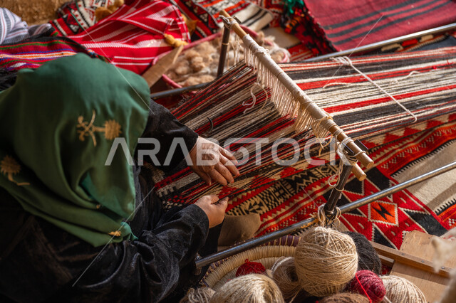 Local national product, our day is February 22, a historical traditional industry, the anniversary of the founding of the first Saudi state in 1727 AD, a picture from above of a Saudi Gulf Arab woman wearing an abaya and a burqa, weaving and spinning wool, an ancient profession and handicraft, reviving Saudi folk heritage