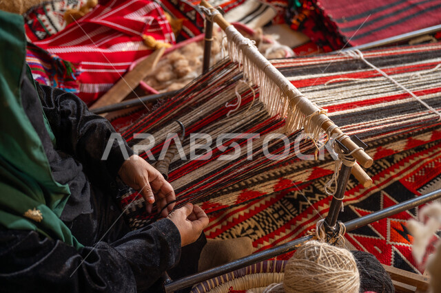صناعة تقليدية تاريخية، منتج وطني محلي, حرفة ومهنة يدوية قديمة، يوم بدينا ٢٢ فبراير، صورة مقربة لأيدي سيدة عربية خليجية سعودية ترتدي العباءة والبرقع تقوم بنسج وغزل الصوف, ذكرى تاسيس الدوله السعوديه الاولى ١٧٢٧م، احياء التراث الشعبي السعودي