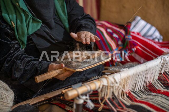 الاستعداد لنسج الصوف, مهنة وحرفة يدوية تاريخيه, المحافظة على التراث السعودي، ذكرى تأسيس الدولة السعودية الأولى 1727م, صورة مقربة لسيدة عربيه خليجية سعودية ترتدي العباءه السوداء و البرقع تقوم بجمع الخيوط، يوم بدينا 22 فبراير