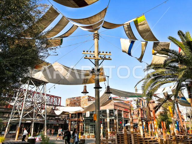 صورة لأشرعة على السقف بين المباني , مظلات قماشية تحمي من أشعة الشمس , تصاميم تشبه الشراع تعطي ظل للمكان .