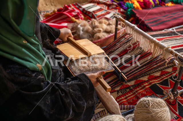 يوم بدينا 22 فبراير, حرفة و مهنه يدوية تاريخيه, المحافظة على التراث السعودي، الاستعداد لنسج وغزل الخيوط, ذكرى تأسيس الدولة السعودية الأولى 1727م, صورة مقربة من الجانب لسيدة عربيه خليجية سعودية ترتدي العباءه السوداء تقوم بتمشيط الصوف