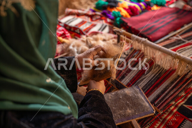 مهنه و حرفة يدوية تاريخيه, المحافظة على التراث السعودي، يوم بدينا 22 فبراير, ذكرى تأسيس الدولة السعودية الأولى 1727م, الاستعداد لنسج وغزل الخيوط, صورة مقربة لسيدة عربيه خليجية سعودية ترتدي العباءه السوداء تقوم بتمشيط الصوف