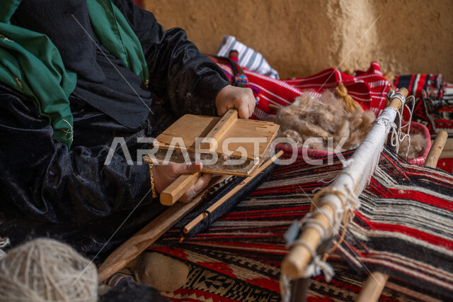 مهنه و حرفة يدوية تاريخيه, المحافظة على التراث السعودي، يوم بدينا 22 فبراير, ذكرى تأسيس الدولة السعودية الأولى 1727م, الاستعداد لنسج وغزل الخيوط, صورة مقربة لسيدة عربيه خليجية سعودية ترتدي العباءه السوداء و البرقع تقوم بتمشيط الصوف