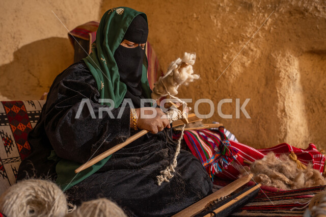 الشغف في ممارسة مهنة الغزل و النسج, يوم بدينا 22 فبراير, ذكرى تأسيس الدولة السعودية الأولى 1727م, امرأة عربيه خليجية سعودية ترتدي البرقع و العباءه السوداء تقوم بلف خيوط الصوف, حرفة يدوية تاريخيه, المحافظة على التراث الشعبي السعودي