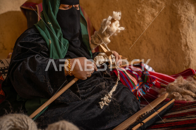 المحافظة على التراث الشعبي السعودي, الشغف في ممارسة مهنة الغزل و النسج, يوم بدينا 22 فبراير, ذكرى تأسيس الدولة السعودية الأولى 1727م, امرأة عربيه خليجية سعودية ترتدي البرقع و العباءه السوداء تقوم بلف خيوط الصوف, حرفة يدوية تاريخيه