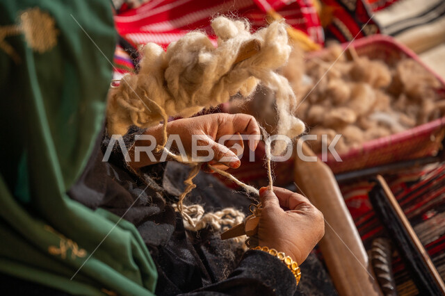 حرفة يدوية تاريخيه, المحافظة على التراث الشعبي السعودي, يوم بدينا 22 فبراير, ذكرى تأسيس الدولة السعودية الأولى 1727م, الشغف في ممارسة مهنة الغزل و النسج, صورة مقربة من الجانب لامرأة عربيه خليجية سعودية ترتدي البرقع و العباءه السوداء تقوم بلف خيوط الصوف