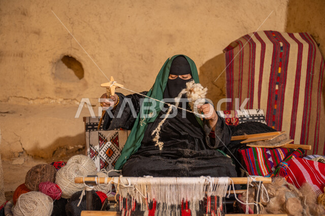 حرفة يدوية تاريخيه, الشغف في ممارسة مهنة الغزل و النسج, يوم بدينا 22 فبراير, المحافظة على التراث الشعبي السعودي, ذكرى تأسيس الدولة السعودية الأولى 1727م, امرأة عربيه خليجية سعودية ترتدي العباءه السوداء و البرقع تقوم بلف خيوط الصوف