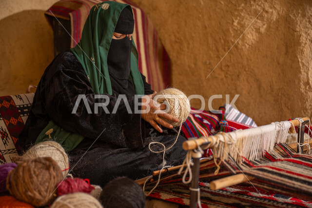 حرفة يدوية تاريخيه, ذكرى تأسيس الدولة السعودية الأولى 1727م, المحافظة على التراث الشعبي السعودي, الشغف في ممارسة مهنة الغزل و النسج, امرأة عربيه خليجية سعودية ترتدي البرقع و العباءه السوداء تقوم بلف خيوط الصوف, يوم بدينا 22 فبراير
