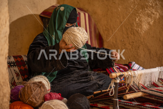 المحافظة على التراث الشعبي السعودي, يوم بدينا 22 فبراير، الشغف في ممارسة مهنة الغزل و النسج, ذكرى تأسيس الدولة السعودية الأولى 1727م, امرأة عربيه خليجية سعودية ترتدي البرقع و العباءه السوداء تقوم بلف خيوط الصوف, حرفة يدوية تاريخيه