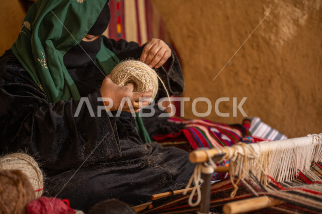 الشغف في ممارسة مهنة الغزل و النسج, حرفة يدوية تاريخيه, ذكرى تأسيس الدولة السعودية الأولى 1727م, المحافظة على التراث الشعبي السعودي, امرأة عربيه خليجية سعودية ترتدي البرقع و العباءه السوداء تقوم بلف خيوط الصوف, يوم بدينا 22 فبراير