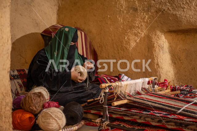 ذكرى تأسيس الدولة السعودية الأولى 1727م, المحافظة على التراث الشعبي السعودي, حرفة يدوية تاريخيه, الشغف في ممارسة مهنة الغزل و النسج, امرأة عربيه خليجية سعودية ترتدي البرقع و العباءه السوداء تقوم بلف خيوط الصوف, يوم بدينا 22 فبراير