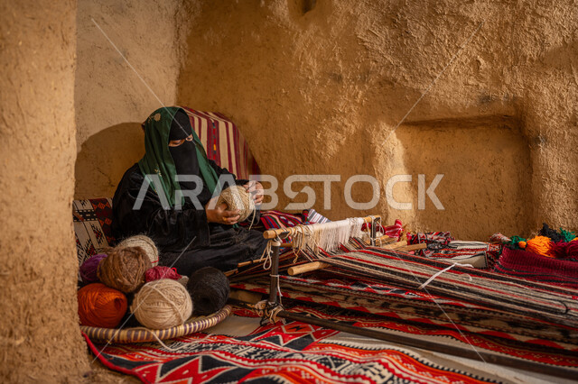 حرفة يدوية تاريخيه, ذكرى تأسيس الدولة السعودية الأولى 1727م, المحافظة على التراث الشعبي السعودي, الشغف في ممارسة مهنة الغزل و النسج, امرأة عربيه خليجية سعودية ترتدي البرقع و العباءه السوداء تقوم بلف خيوط الصوف, يوم بدينا 22 فبراير
