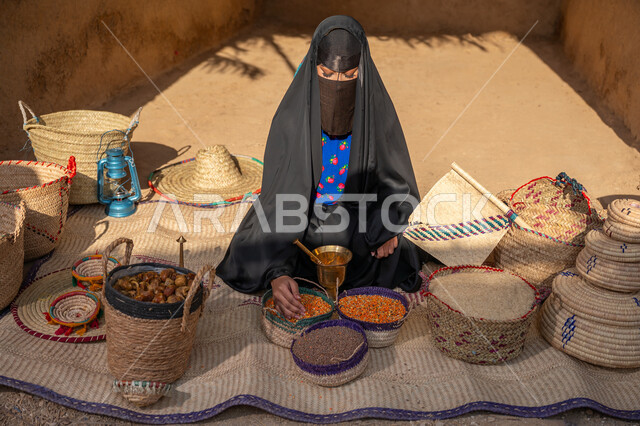 يوم بدينا 22 فبراير, ذكرى تأسيس الدولة السعودية الأولى 1727م, عرض الحبوب والمنتج المحلي الوطني في سلل من الحصير اليدوي، المحافظة على التراث السعودي ،بائعه عربيه خليجية سعودية ترتدي العباءه السوداء و البرقع تقوم ببيع العدس و البقوليات على بساط شعبي