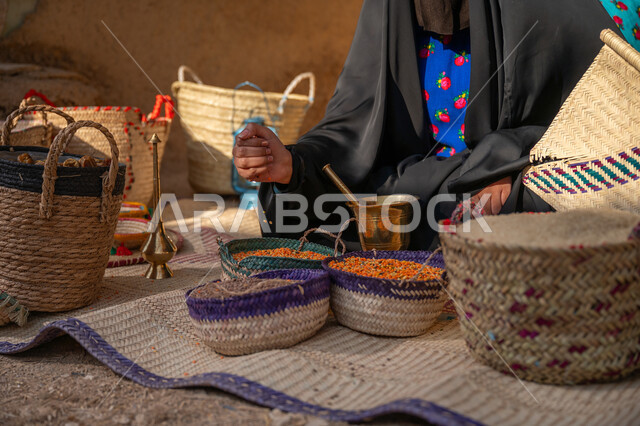 ذكرى تأسيس الدولة السعودية الأولى 1727م, عرض الحبوب والمنتج المحلي الوطني في سلل من الحصير اليدوي، المحافظة على التراث السعودي ،صورة مقربة لبائعه عربيه خليجية سعودية ترتدي العباءه السوداء تقوم ببيع العدس و البقوليات على بساط شعبي، يوم بدينا 22 فبراير