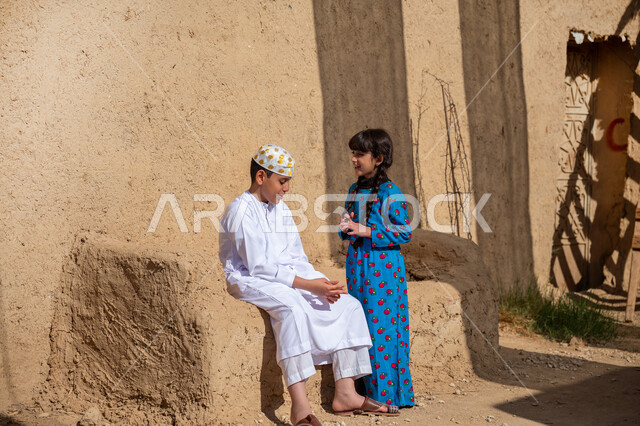 قضاء وقت ممتع في التحدث والنقاش مع الأخ، قرية تاريخية مبنية من الطوب، يوم بدينا 22 فبراير، ولد وأخته عربيان خيليجيان سعوديان يرتديان الأزياء الشعبية يجلسان في منزل طيني قديم ويتبادلان أطراف الحديث، إحياء ذكرى تأسيس الدولة السعودية الأولى 1727 م