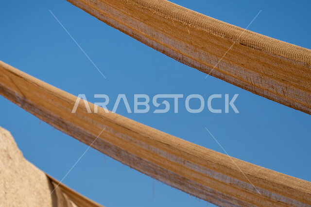 قماش ممتد بين البيوت لتوفير الظل بطريقة قديمة متوارثة، بيت تراثي طيني مبني من الطوب على الطراز القديم, المباني الأثرية التاريخية في المملكة, ذكرى يوم تأسيس الدولة السعودية الأولى 1727 م، يوم بدينا 22 فبراير, صورة مقربة للمظلة القماشية، خلفية السماء الصافية