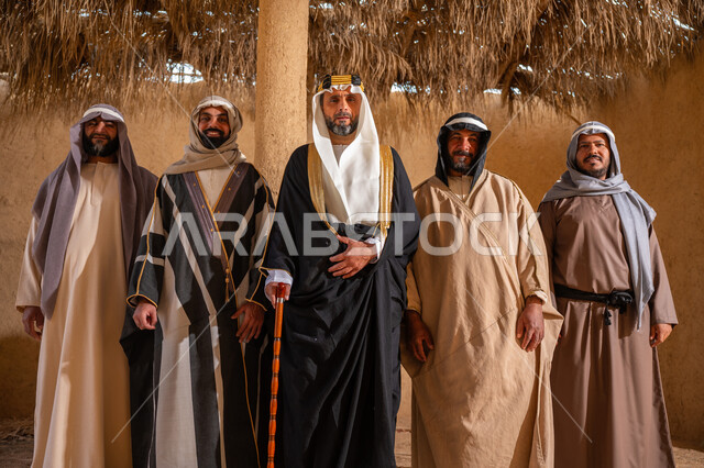 ذكرى تأسيس الدولة السعودية الأولى 1727م، إظهار الولاء والحب للوطن, مجموعة رجال عرب خليجين سعوديين يرتدون الزي الشعبي التقليدي في المناسبة الوطنية يقفون في بيت من الطين ينظرون إلى الكاميرا بتعابير الشموخ، إيماءات الثقة والفخر بإنجازات المملكة، يوم بدينا 22 فبراير