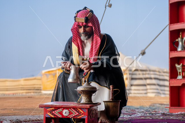تعابير الاعتزاز والفخر، يوم بدينا 22 فبراير، الزي الشعبي في المناسبة الوطنية, مفهوم حسن الضيافة و الاستقبال، ذكرى تأسيس الدولة السعودية الأولى في 1727م، رجل عربي خليجي سعودي يرتدي العقال الذهبي والبشت يجلس بجوار الخيمة في الصحراء يحمل بيده دلة قهوة نحاسية