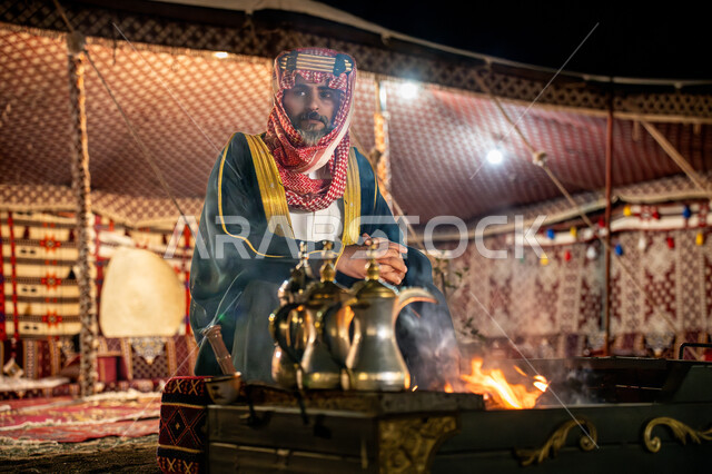 النظر الى شيء ما بتعابير الفخر, مناسبة و احتفال وطني, خيمة شعبية في الصحراء، يوم بدينا 22 فبراير، ذكرى تاسيس الدوله السعوديه الاولى 1727م, رجل عربي خليجي سعودي يرتدي البشت و الشماغ التقليدي يجلس أمام شعلة النار، اجواء شتوية ليلية