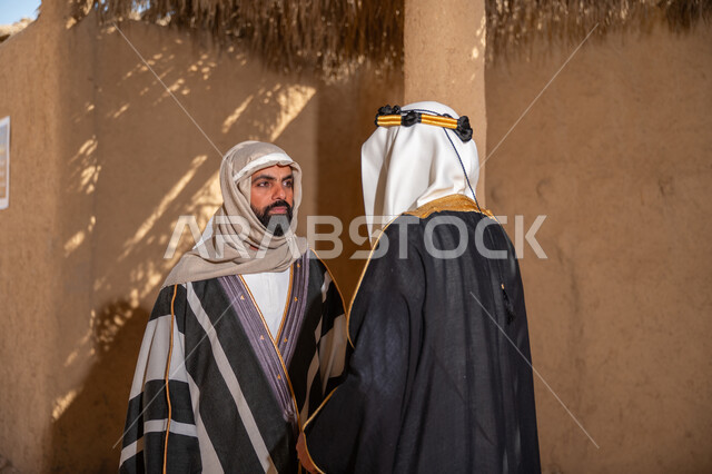 الشموخ والاعتزاز والفخر، رجلان عربيان خليجيان سعوديان يرتديان الزي الشعبي في المناسبة الوطنية يقفان داخل منزل من الطين, ذكرى تأسيس الدولة السعودية الأولى في 1727م، يوم بدينا 22 فبراير، إظهار حب الوطن والانتماء إليه