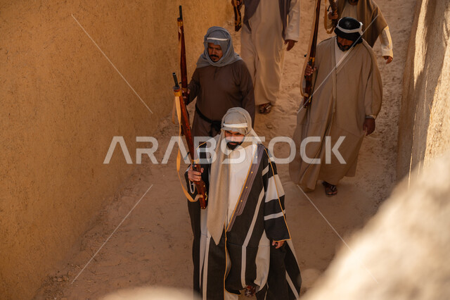 الحفاظ على تاريخ وتراث المملكة، القتال والحرب بالبنادق للحماية وتأسيس الدولة السعودية الأولى 1727م، مجموعة رجال عرب خليجيين سعوديين يرتدون الزي الشعبي التقليدي يحملون البندقيات، الحراسة والمراقبة للدفاع عن الوطن، يوم بدينا 22 فبراير