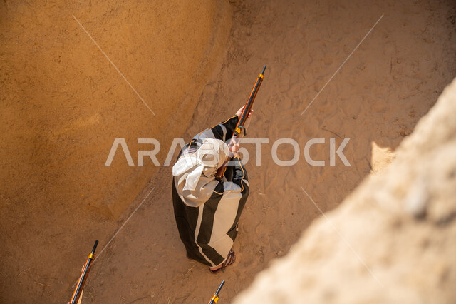 يوم بدينا 22 فبراير، الحفاظ على تاريخ وتراث المملكة، القتال والحرب بالبنادق للحماية وتأسيس الدولة السعودية الأولى 1727م، رجل عربي خليجي سعودي يرتدي الزي الشعبي التقليدي يحمل البندقية، الحراسة والمراقبة للدفاع عن الوطن
