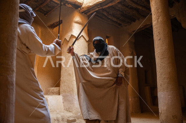 الحفاظ على تاريخ وتراث المملكة، أدوات الحرب القديمة، المبارزة بالسيف للحماية وتأسيس الدولة السعودية الأولى 1727م، رجلان عربيان خليجيان سعوديان يرتديان الزي الشعبي يتبارزان بالسيوف في بيت طيني، مفهوم الحرب والدفاع عن الوطن، يوم بدينا 22 فبراير