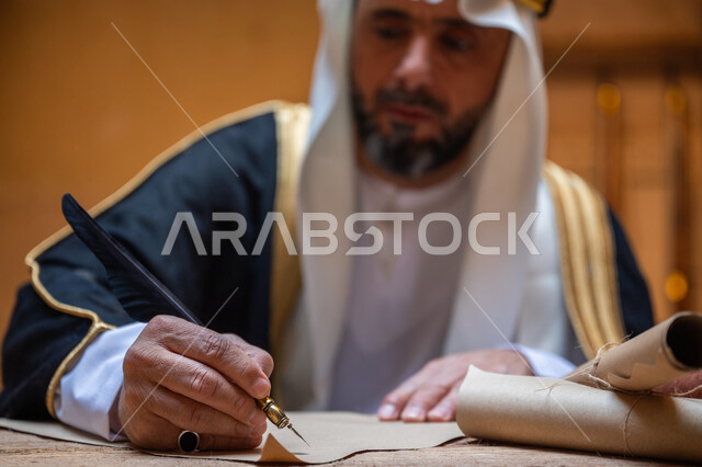 يوم بدينا 22 فبراير، ارتداء الزي الشعبي في المناسبة الوطنية، صورة مقربة لرجل عربي خليجي سعودي يرتدي الغترة والبشت يمسك بيده الريشة يقوم بالكتابة على مخطوطة جلد تاريخية، الخطابات والمراسلات التراثية لتأسيس الدولة السعودية الأولى 1727م، الفخر بأصالة المملكة